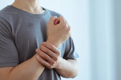 Patient holding his wrist in pain from lingering nerve damage, in need of peripheral nerve surgery.