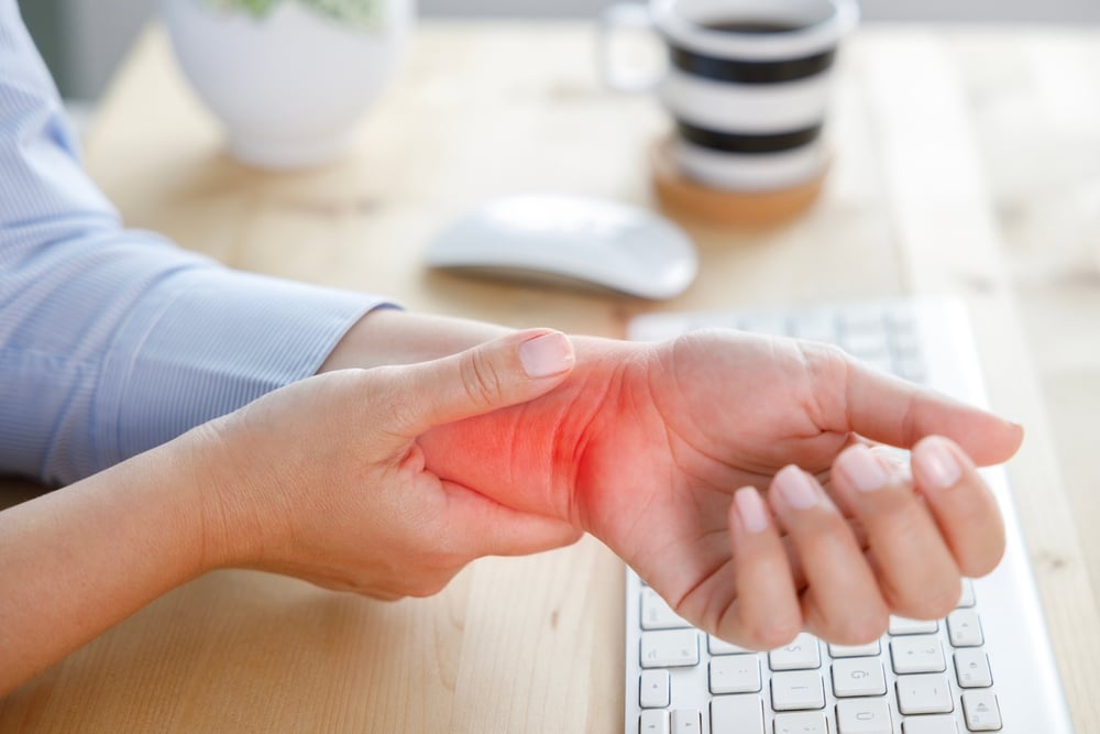 Close-up of a woman massaging her hand and her wrist in pain from carpal tunnel or a like nerve condition.