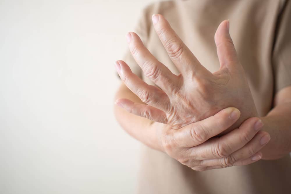 Patient with a nerve injury clutching their hand in pain, in need of a nerve repair treatment.